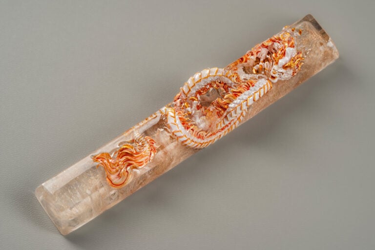 Intricately carved orange dragon in crystal cylinder.