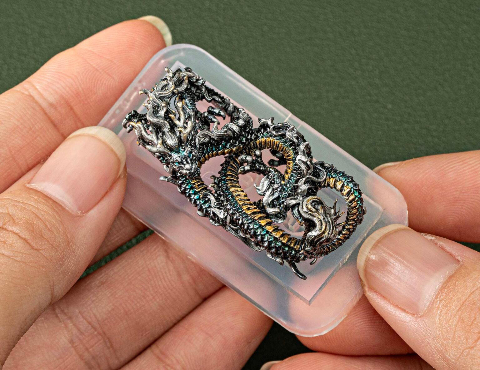 Hand holding intricate dragon sculpture keycaps in resin.