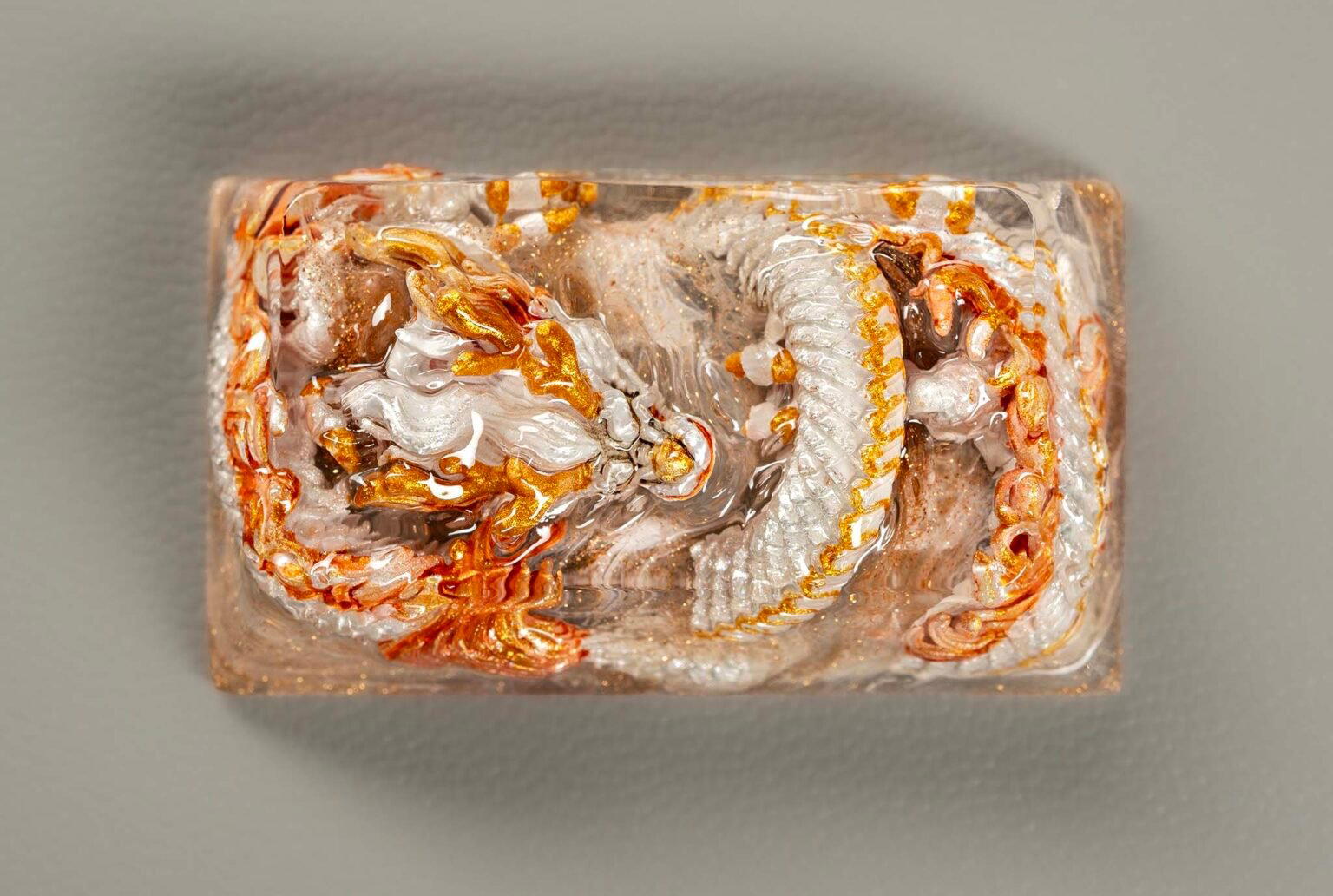 Decorative glass paperweight with gold and silver dragons.