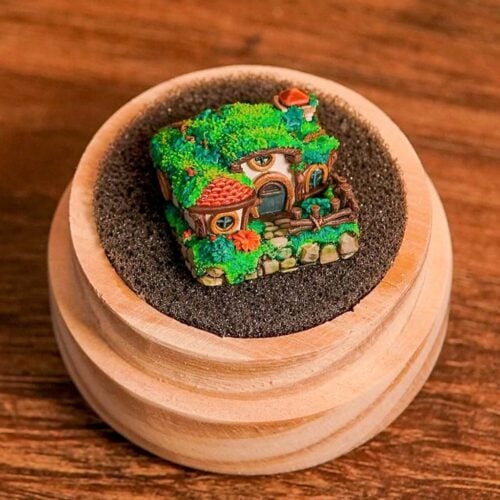 Miniature fairy house in a wooden bowl on table.